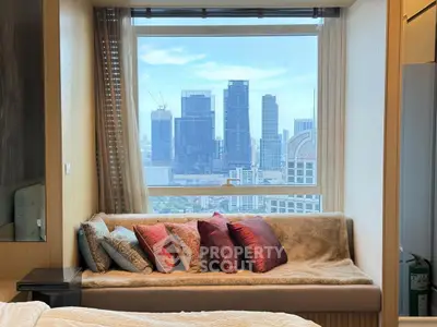 Luxurious bedroom with stunning city view from large window, featuring cozy seating area with plush cushions.