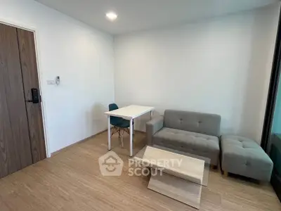 Modern minimalist living room with cozy gray sofa and sleek wooden flooring.