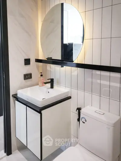 Modern bathroom with sleek sink and round mirror in stylish apartment.