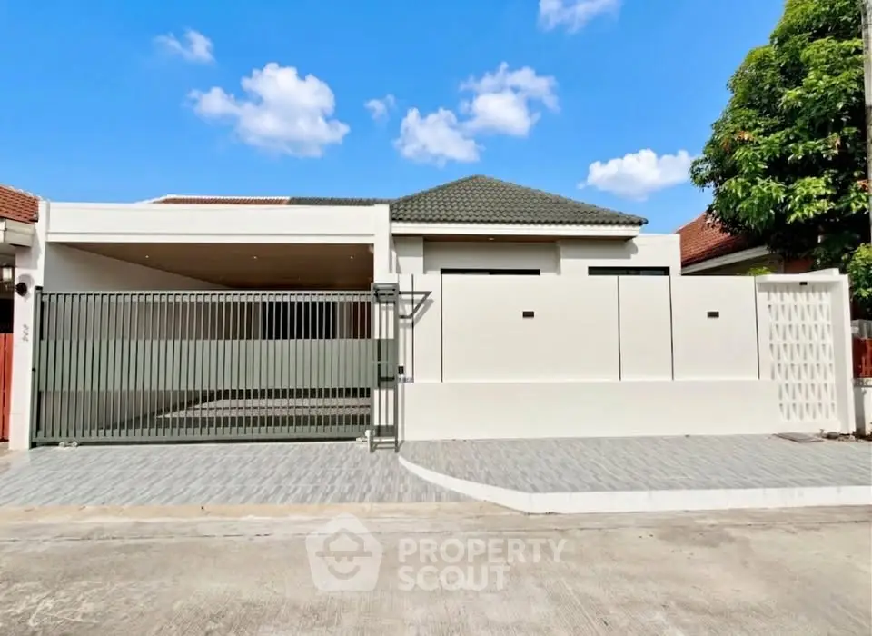 Modern single-story house with gated driveway and sleek exterior design under a clear blue sky.