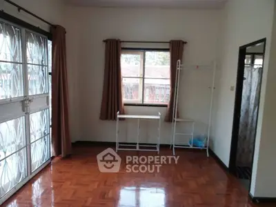 Spacious room with wooden flooring and large windows for natural light.