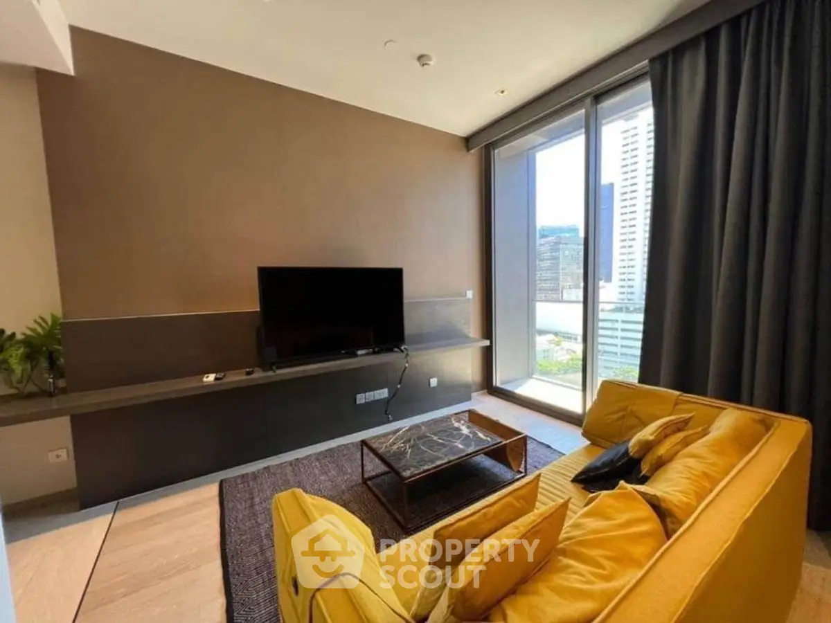 Modern living room with yellow sofa and large TV, featuring floor-to-ceiling windows with city view.
