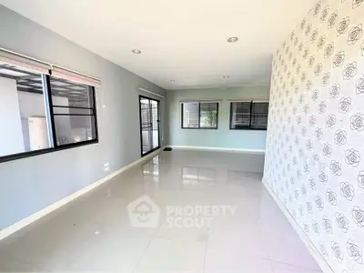 Spacious modern living room with large windows and stylish wallpaper accent wall.