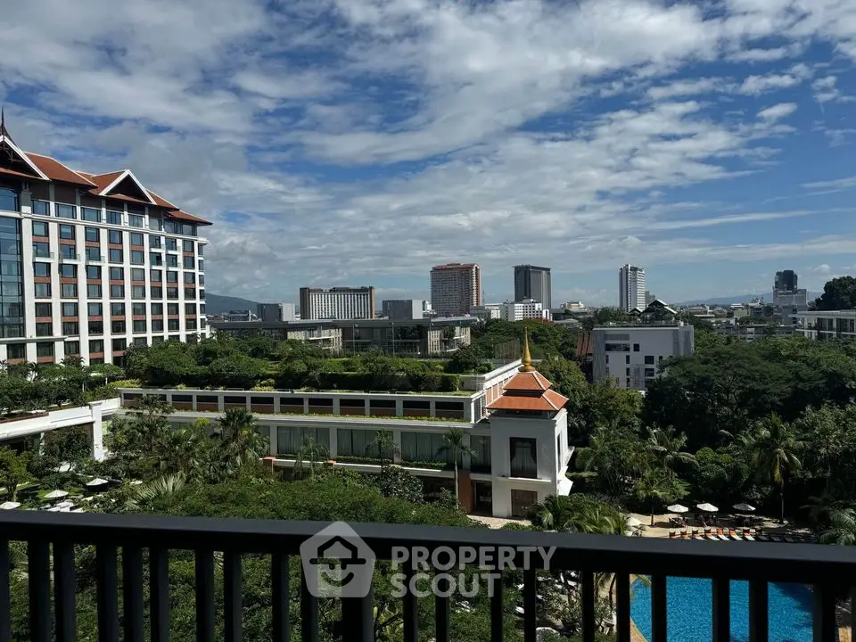 Stunning cityscape view from a high-rise balcony overlooking lush greenery and a pool.