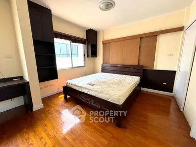 Spacious bedroom with wooden flooring and large window for natural light