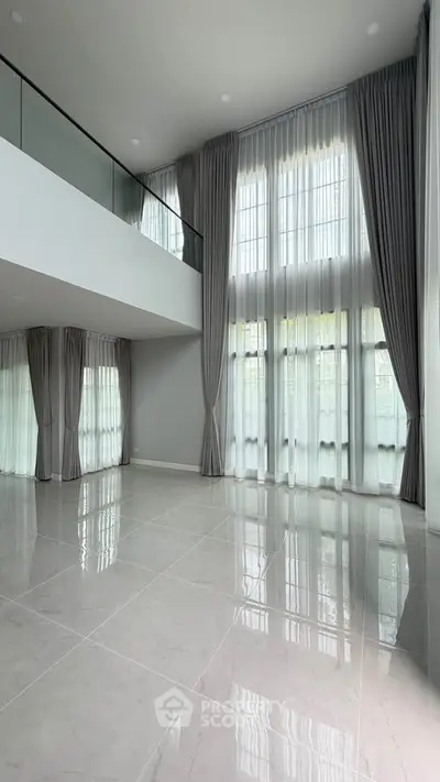 Spacious modern living room with high ceilings and large windows, perfect for natural light.