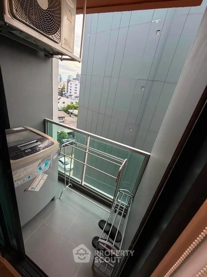 Compact balcony with washing machine and city view, ideal for urban living.