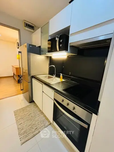 Modern kitchen with sleek appliances and open layout, featuring a built-in oven and stylish cabinetry.