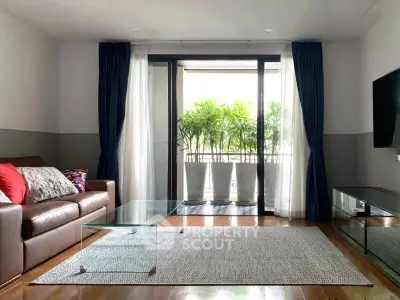 Spacious living room with glass coffee table and balcony view, perfect for relaxation.