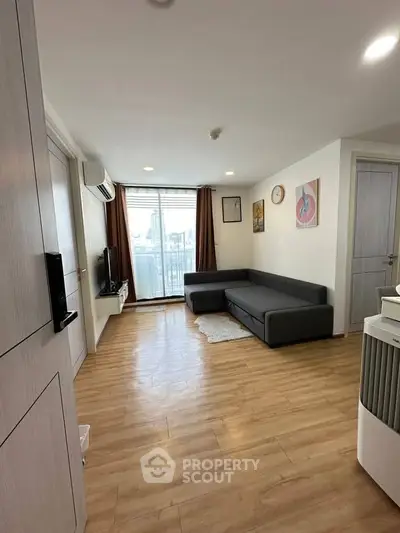 Modern living room with wooden flooring and city view balcony in a stylish apartment.