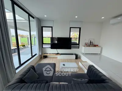 Modern living room with large windows and stylish furniture overlooking a scenic view.