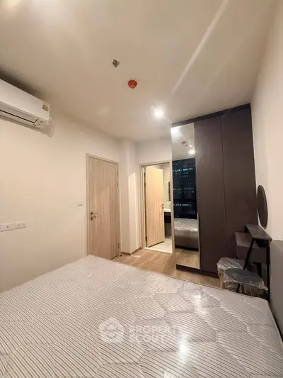 Modern bedroom with sleek wardrobe and air conditioning in a stylish apartment.