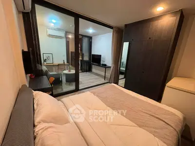 Modern bedroom with glass partition leading to cozy living area