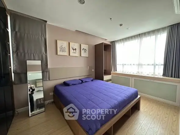 Spacious bedroom with modern decor and large window for natural light