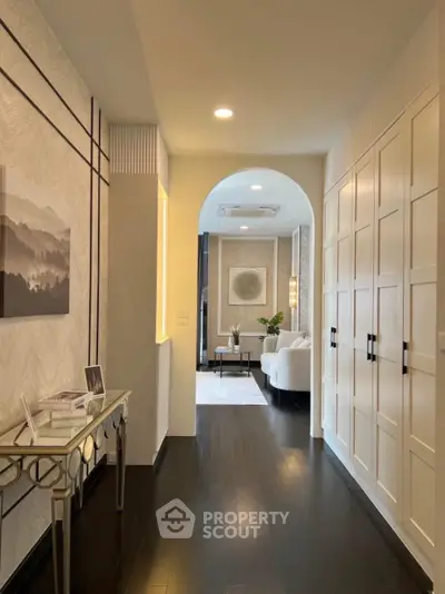 Elegant hallway leading to a stylish living room with modern decor and dark wood flooring.