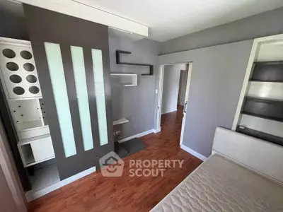 Modern bedroom with sleek design and wooden flooring, featuring built-in shelves and a stylish partition.
