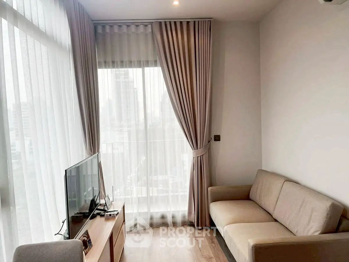 Cozy living room with city view, modern sofa, and natural light through large windows.