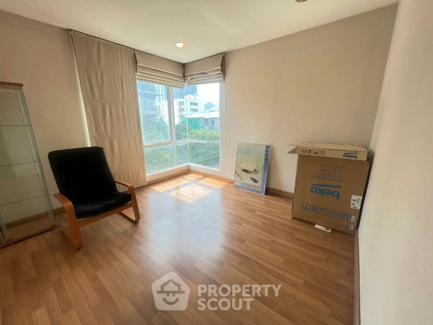 Bright and airy room with large window and wooden flooring, perfect for a cozy living space.