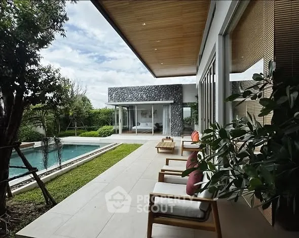 Luxurious modern home with spacious patio and pool, surrounded by lush greenery, perfect for relaxation and entertaining.