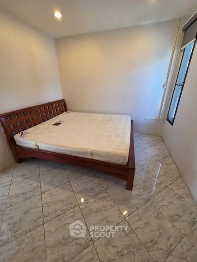 Spacious bedroom with elegant wooden bed and tiled flooring