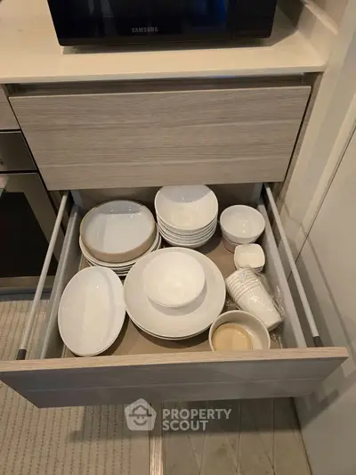 Modern kitchen drawer with neatly organized white dishes and bowls in a sleek cabinet.