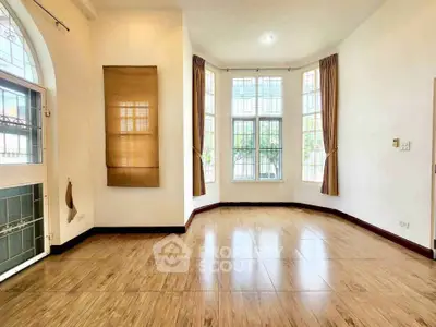 Spacious sunlit room with large windows and elegant wooden flooring, perfect for a cozy living space.