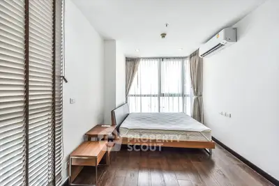 Modern bedroom with wooden flooring and large windows in a stylish apartment.