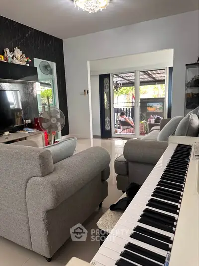 Spacious living room with modern decor and piano, leading to a cozy outdoor area.
