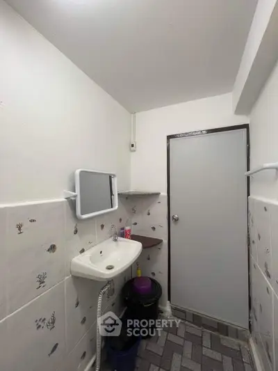 Compact bathroom with wall-mounted sink and decorative tiles.