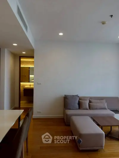 Modern living room with cozy sofa and wooden flooring, adjacent to a stylish bathroom.
