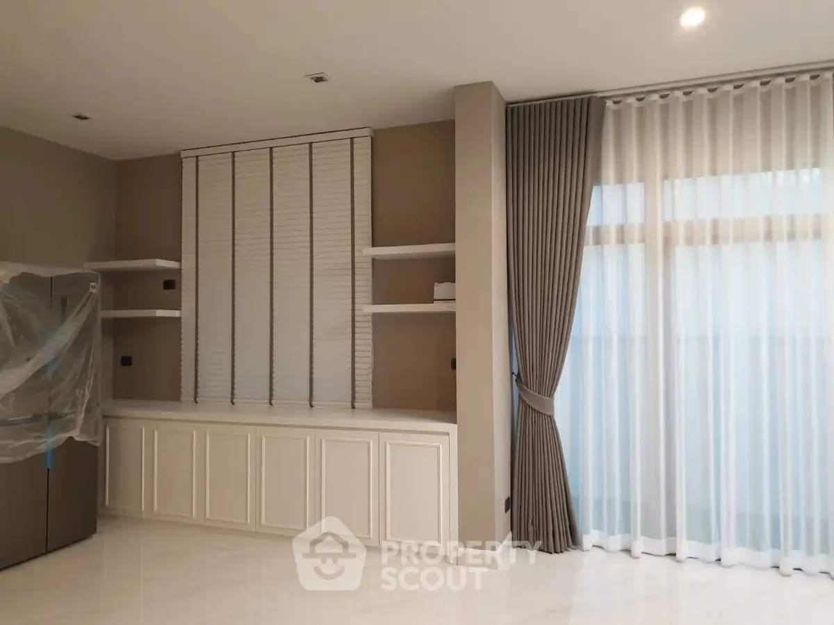 Elegant living room with modern shelving and large windows with curtains