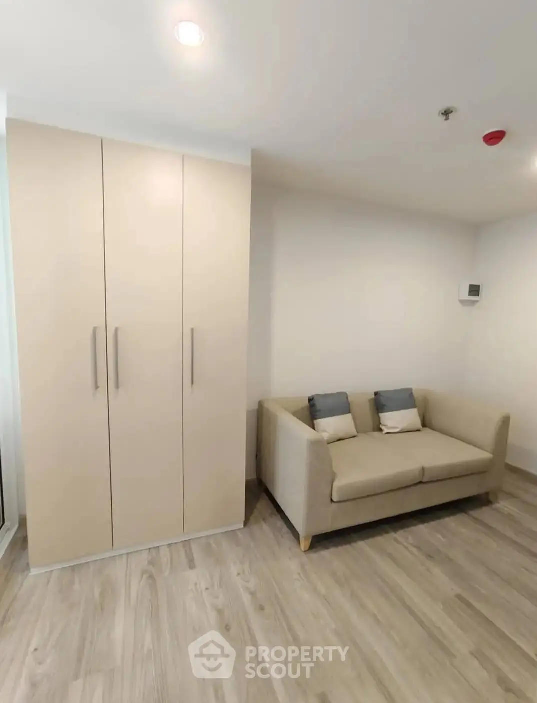 Modern living room with beige sofa and sleek wardrobe, featuring minimalist design and wooden flooring.