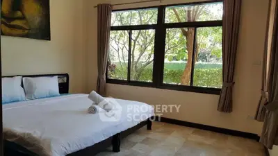 Spacious bedroom with large window and garden view, featuring a comfortable bed and elegant decor.