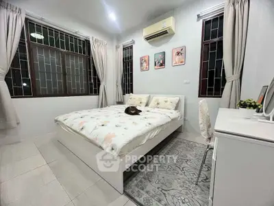 Cozy bedroom with large windows and modern decor, featuring a comfortable bed and stylish furnishings.