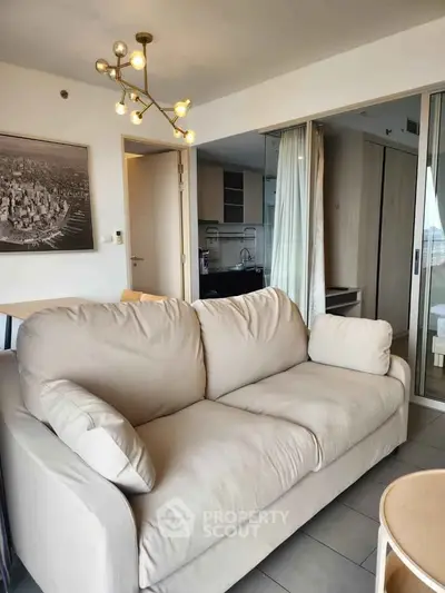 Modern living room with cozy beige sofa and stylish lighting in open-plan apartment.