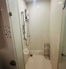 Compact bathroom shower area with glass door and modern fixtures.