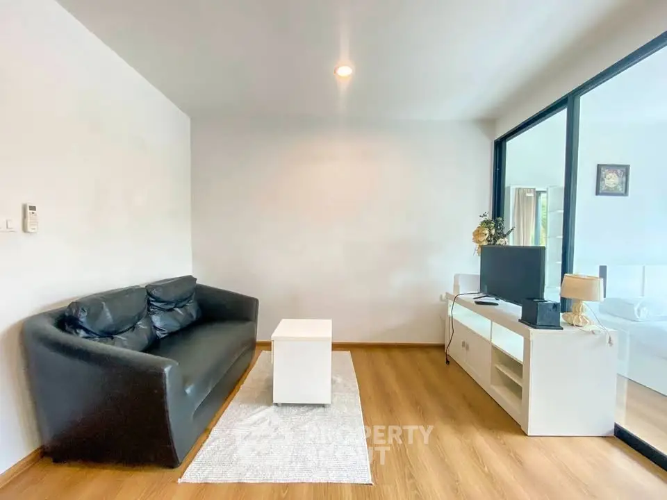 Modern living room with black leather sofa and sleek white furniture, featuring a cozy ambiance and natural light.