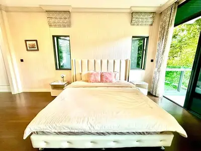Luxurious bedroom with elegant decor and large windows offering a serene garden view.
