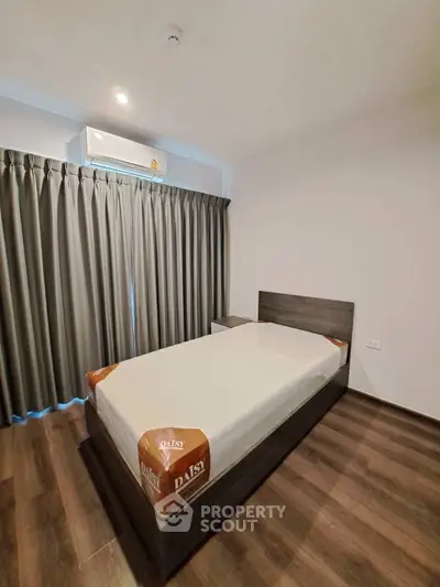 Modern bedroom with sleek design and air conditioning, featuring elegant curtains and wooden flooring.