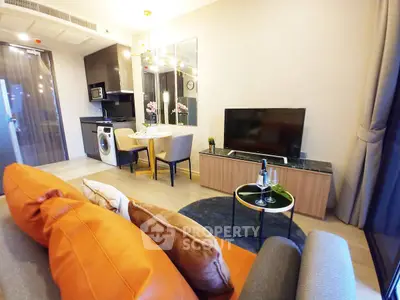 Modern living room with open kitchen, featuring stylish decor and cozy seating area.