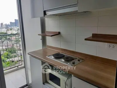 Modern kitchen with electric stove and microwave, featuring a balcony with city view.