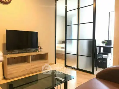 Modern living room with TV and glass partition leading to bedroom in stylish apartment.