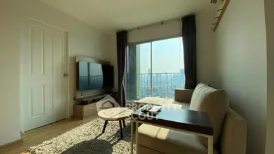 Modern living room with large window and city view, featuring cozy sofa and TV setup.