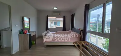 Spacious bedroom with large windows and modern furnishings in a cozy home.