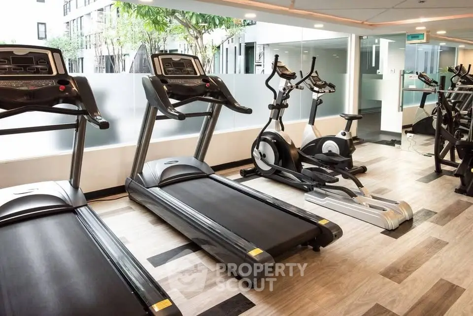 Modern gym with treadmills and exercise bikes in a stylish apartment complex.