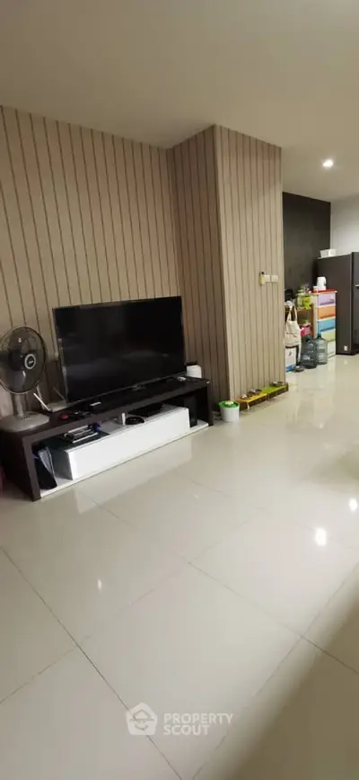 Spacious living room with modern TV setup and sleek tiled flooring