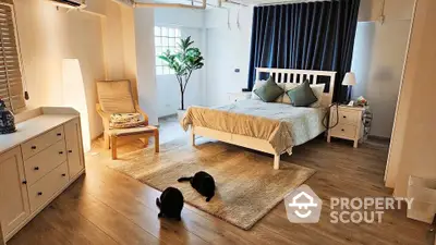 Spacious bedroom with modern decor and cozy ambiance, featuring wooden flooring and stylish furniture.