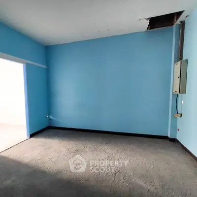 Spacious empty room with blue walls and concrete floor, ideal for customization.