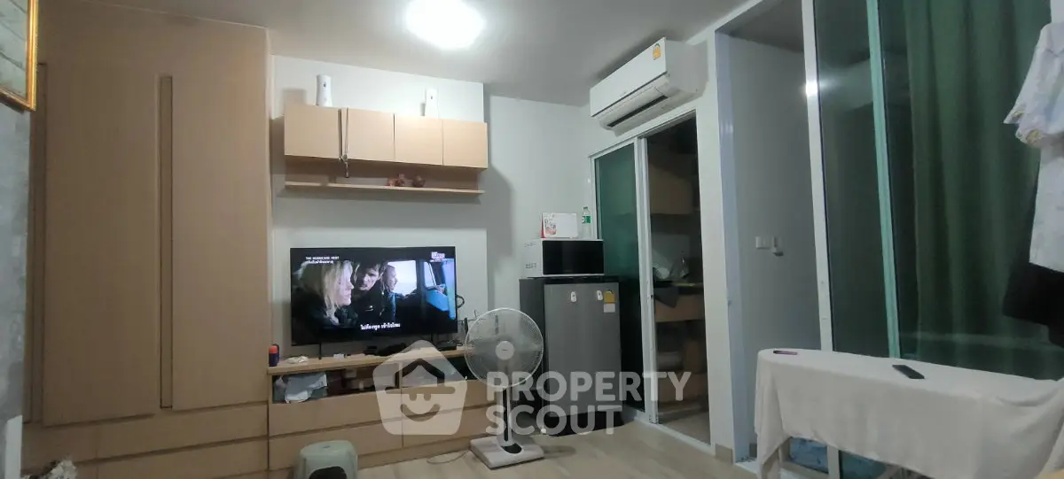 Modern living room with built-in storage, air conditioning, and compact refrigerator.