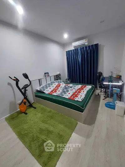Cozy bedroom with exercise bike and modern decor, featuring air conditioning and stylish curtains.